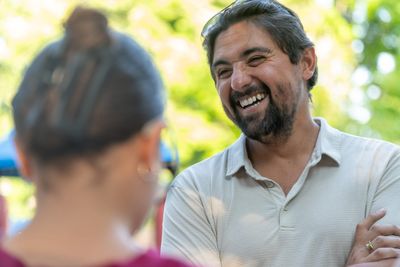 Pete Gonzales laughing during an outdoor conversation with a District 3A resident.