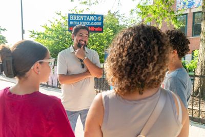 Pete Gonzales talking with three neighbors on the sidewalk outside Brentano Math and Science Academy.