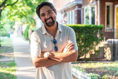 Pete Gonzales standing on a residential sidewalk in District 3A, arms folded.